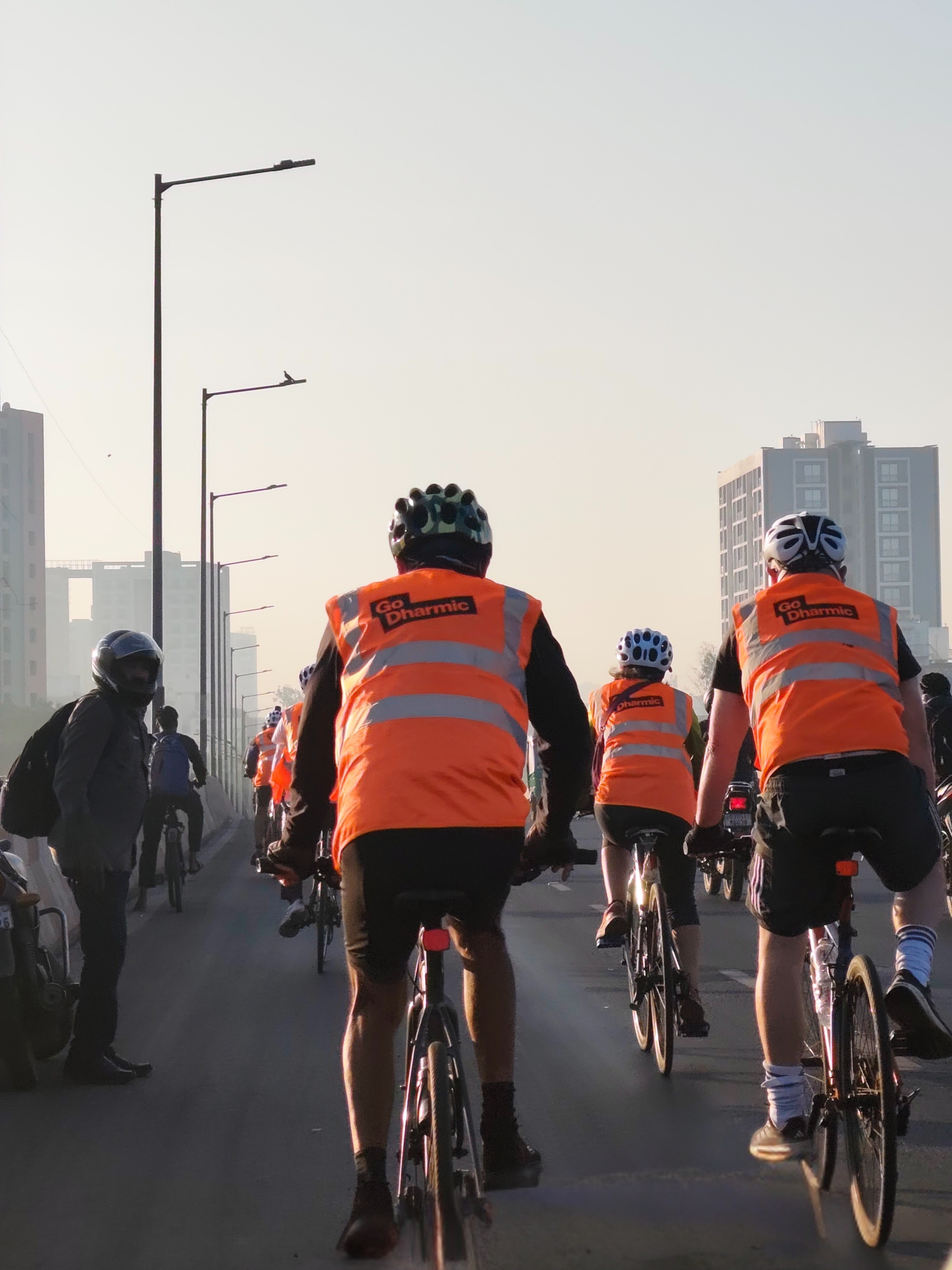 Cyclists riding in India wearing orange vests
