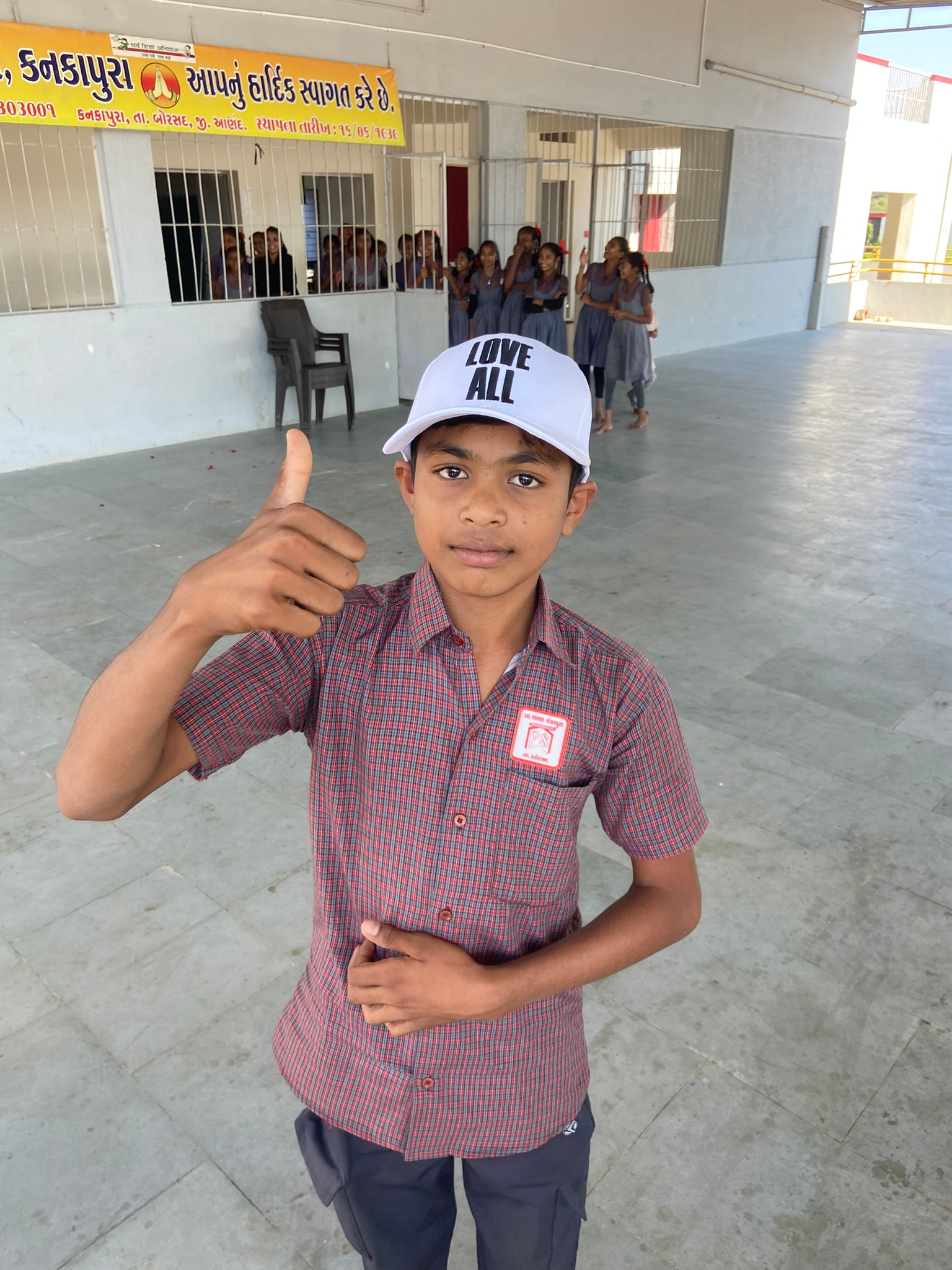 Student wearing a Love All hat giving a thumbs up